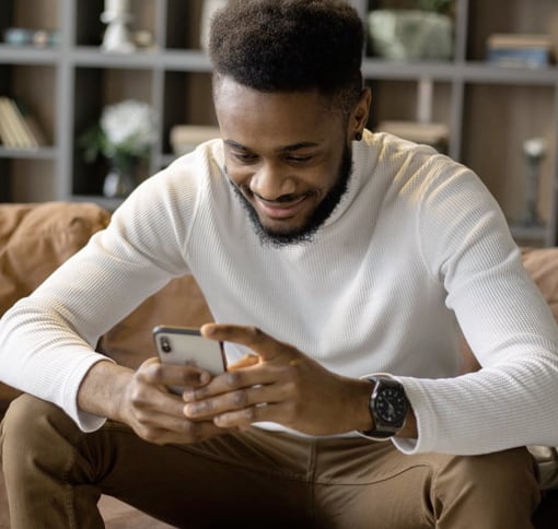 Black man with white sweater is texting on his phone